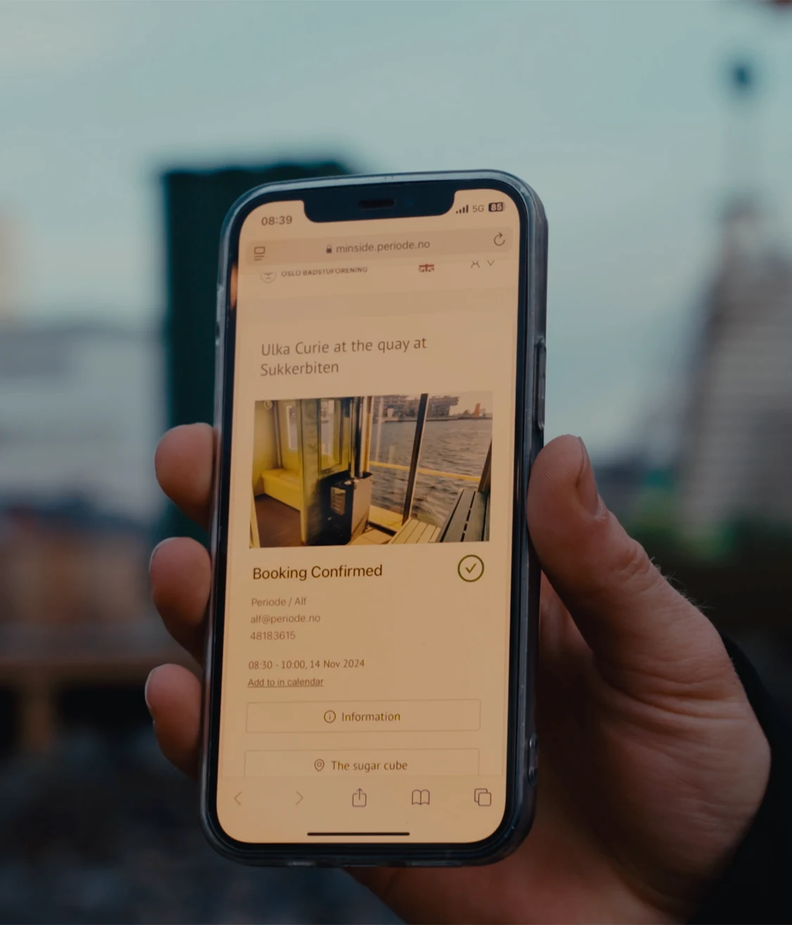 A guest holding a phone with a confirmed sauna booking